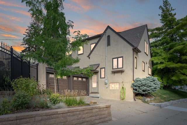 english style home featuring stucco siding and fence