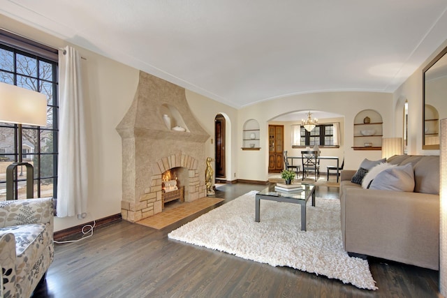 living area featuring built in features, baseboards, wood finished floors, and a fireplace