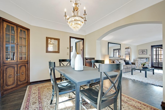 dining room featuring baseboards, arched walkways, a chandelier, and dark wood-style flooring