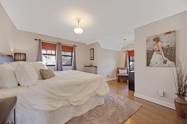 bedroom with baseboards, light wood-style floors, a chandelier, and radiator heating unit