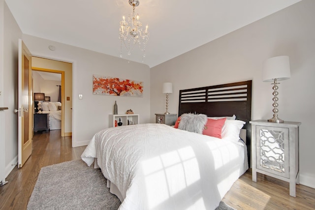 bedroom with vaulted ceiling, a notable chandelier, wood finished floors, and baseboards