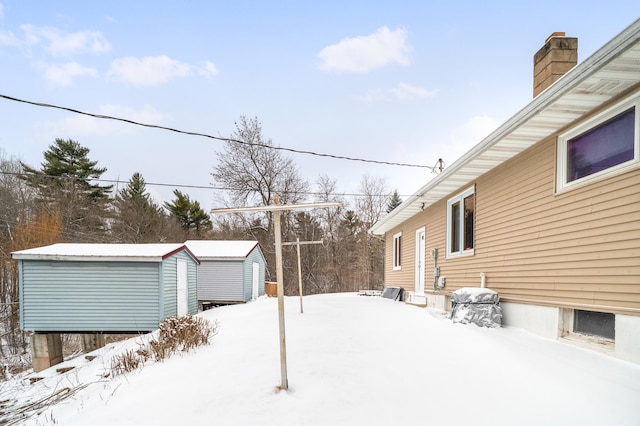 yard covered in snow featuring a storage shed and an outbuilding