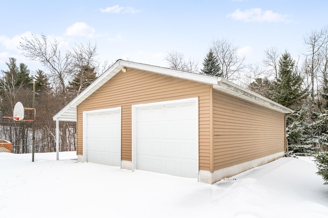 snow covered garage with a detached garage