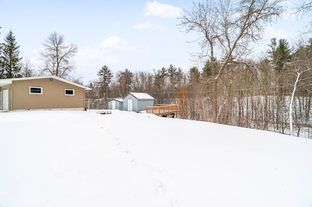 yard covered in snow featuring a garage and an outdoor structure