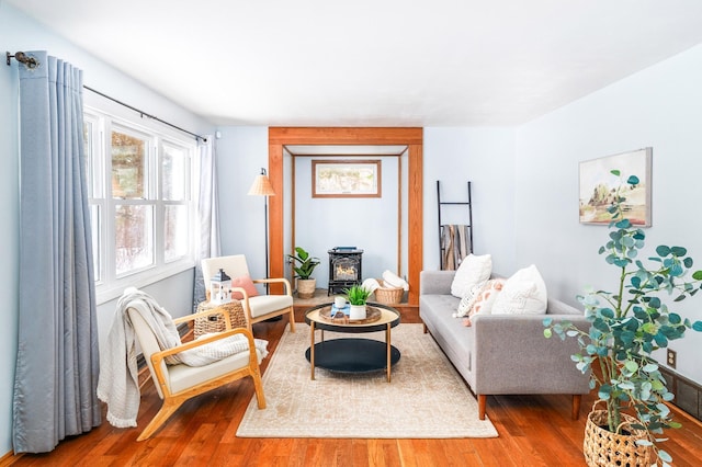 living area with a wood stove and wood finished floors