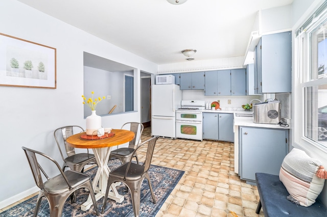 kitchen featuring white appliances, a sink, light countertops, blue cabinetry, and backsplash