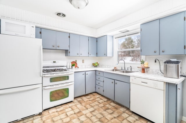 kitchen featuring white appliances, visible vents, light countertops, blue cabinetry, and a sink