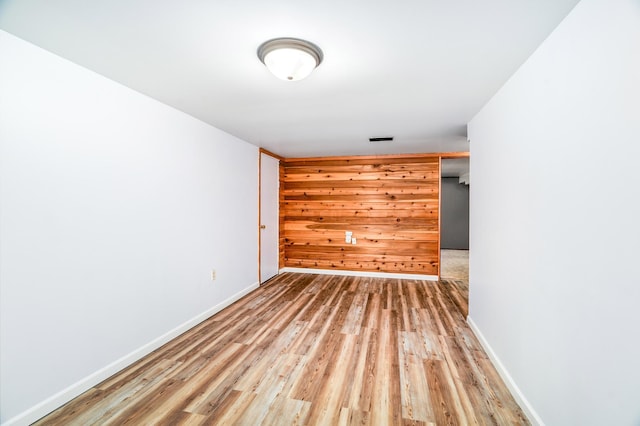 empty room with wood finished floors, visible vents, and baseboards