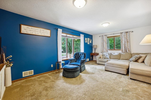 carpeted living area with visible vents, a textured ceiling, and baseboards