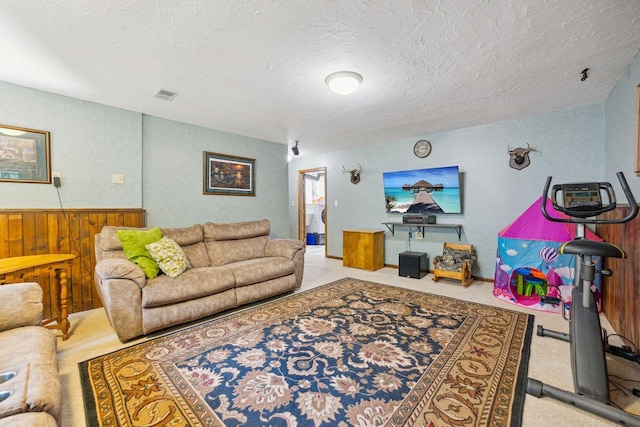 living area featuring visible vents, light carpet, wood walls, and a wainscoted wall