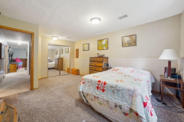 bedroom featuring visible vents, a textured ceiling, a closet, carpet floors, and baseboards