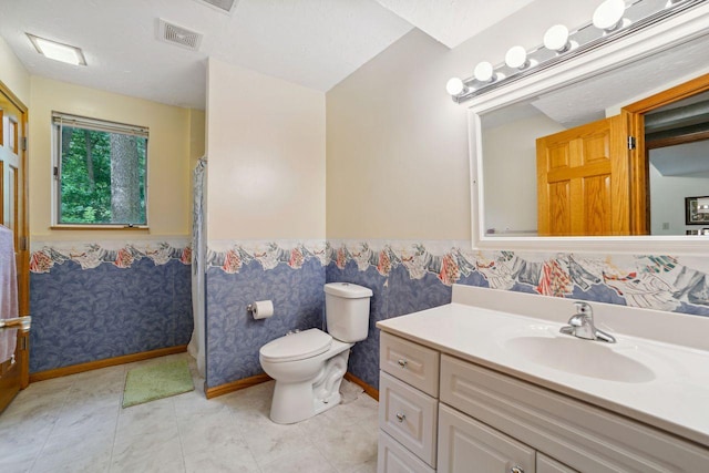 bathroom featuring vanity, visible vents, a wainscoted wall, wallpapered walls, and toilet