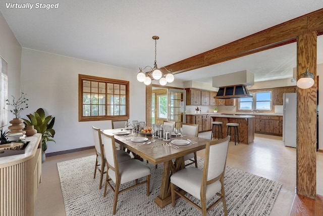 dining room with a chandelier, a wealth of natural light, beamed ceiling, and baseboards