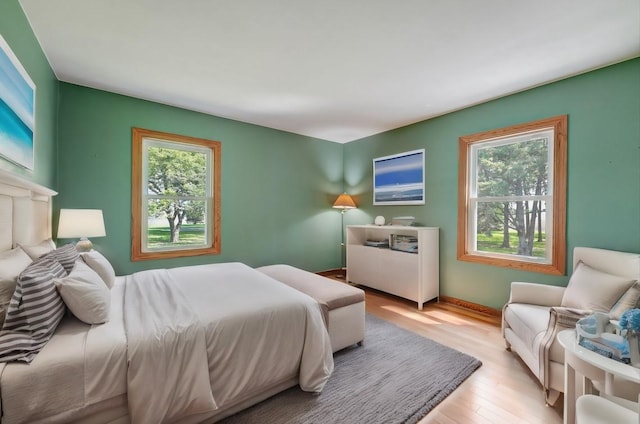 bedroom with light wood finished floors and baseboards