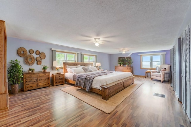 bedroom with visible vents, ceiling fan, a textured ceiling, wood finished floors, and baseboards