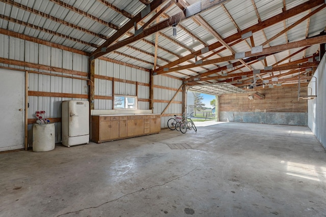 garage with metal wall and freestanding refrigerator