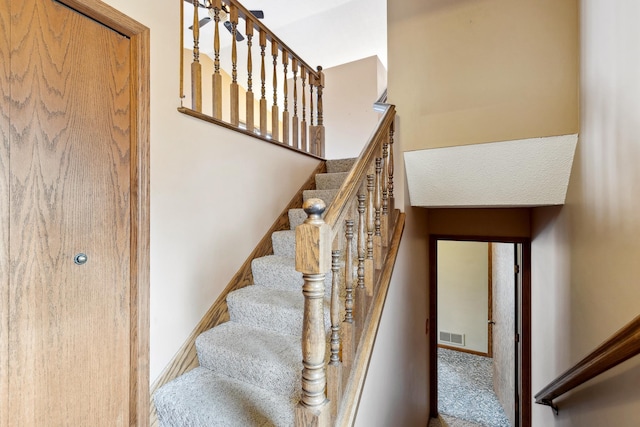 stairway with visible vents, baseboards, and carpet floors