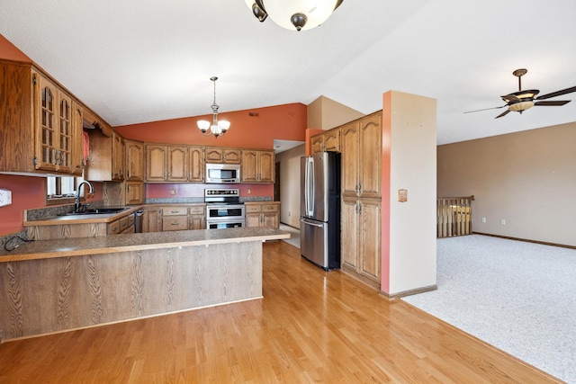 kitchen featuring glass insert cabinets, light wood-style flooring, brown cabinets, appliances with stainless steel finishes, and a peninsula