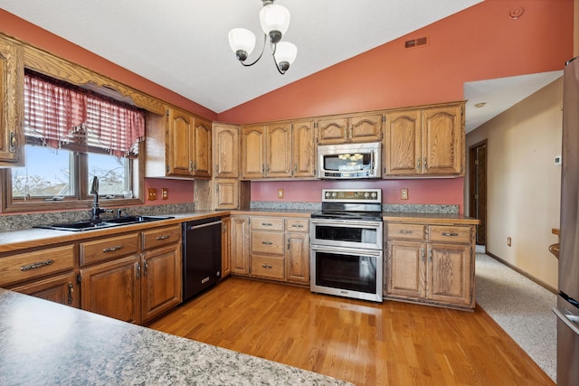 kitchen featuring visible vents, vaulted ceiling, appliances with stainless steel finishes, brown cabinetry, and a sink