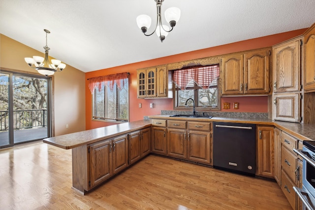 kitchen featuring brown cabinets, a sink, a peninsula, dishwasher, and a chandelier