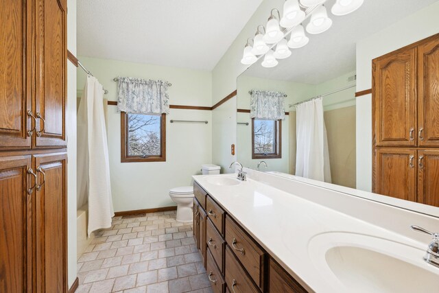 full bathroom featuring a sink, baseboards, toilet, and double vanity