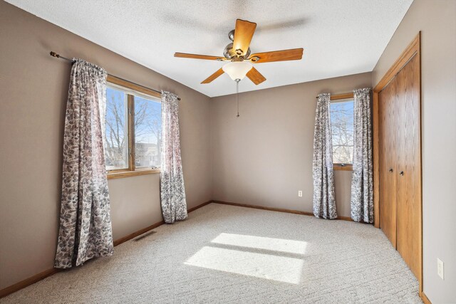 bedroom with visible vents, carpet flooring, a textured ceiling, and baseboards