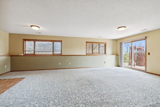 carpeted spare room with baseboards and a textured ceiling