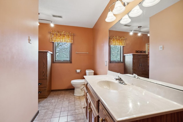 bathroom with vanity, toilet, a healthy amount of sunlight, and baseboards