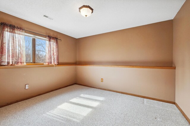 spare room featuring visible vents, baseboards, carpet, and a textured ceiling