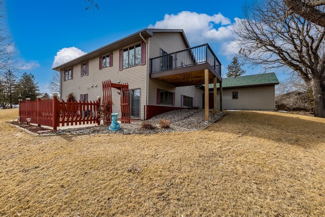 back of property with a deck and a yard