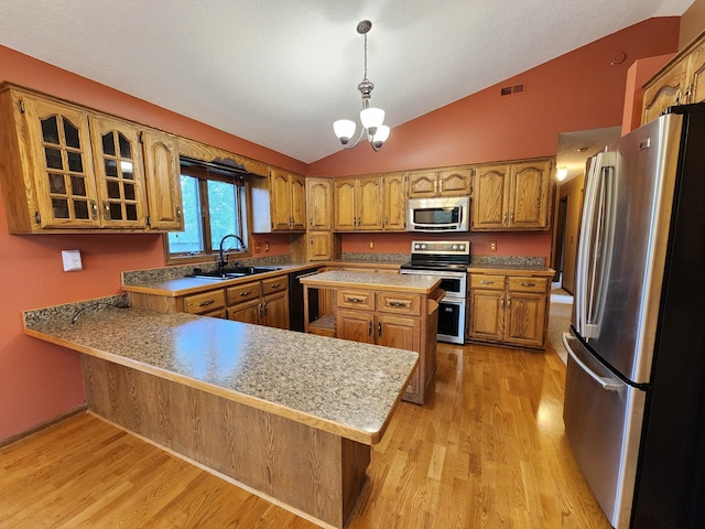 908 Park Ln, Belle Plaine, MN 56011 - kitchen with stainless steel appliances, lofted ceiling, brown cabinets, light wood finished floors, and a peninsula
