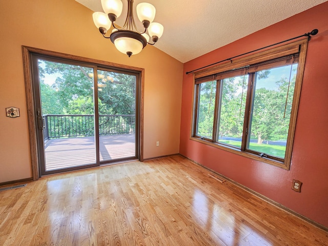 908 Park Ln, Belle Plaine, MN 56011 - empty room with a chandelier, lofted ceiling, plenty of natural light, light wood finished floors, and a textured ceiling