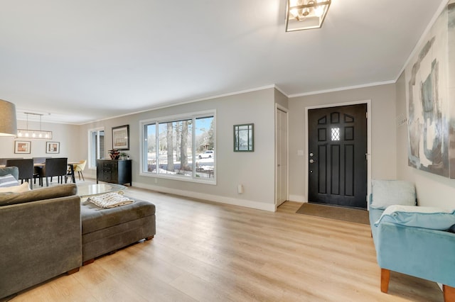 living room featuring crown molding, baseboards, and light wood-type flooring