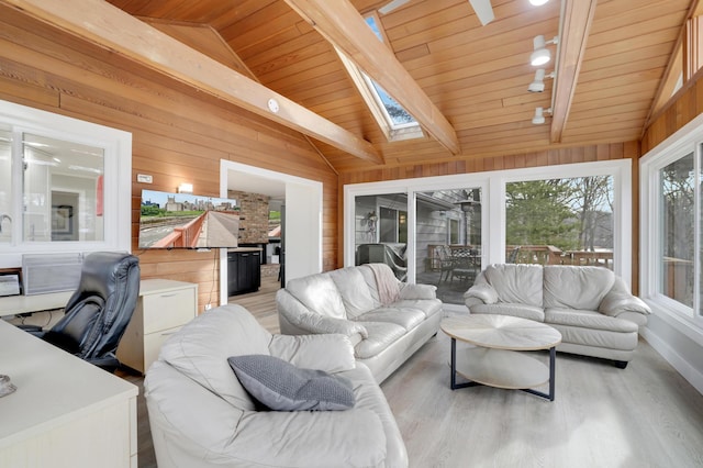 living room featuring vaulted ceiling with skylight, light wood-style floors, wood ceiling, and wood walls