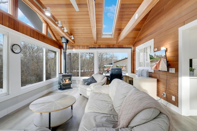 sunroom with track lighting, vaulted ceiling with skylight, wooden ceiling, and a wood stove