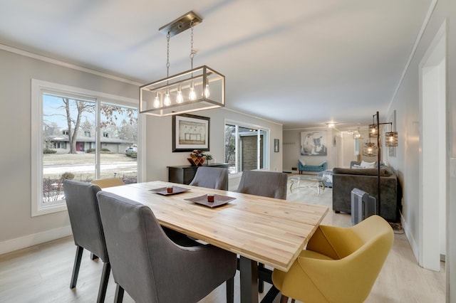 dining area featuring light wood-type flooring, crown molding, and baseboards