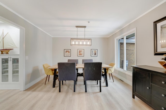 dining space featuring light wood finished floors, crown molding, and baseboards