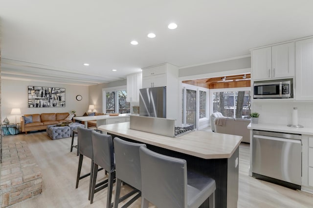 kitchen featuring a kitchen breakfast bar, appliances with stainless steel finishes, white cabinets, and light countertops