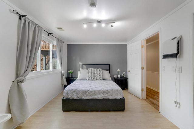 bedroom with light wood-style floors and visible vents