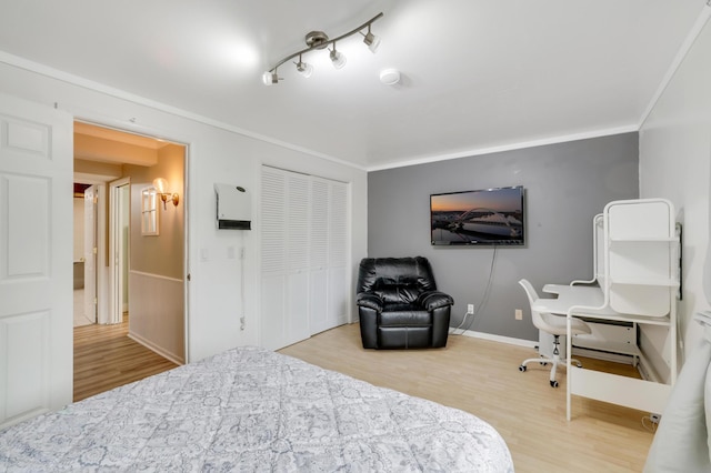 bedroom with crown molding, wood finished floors, and baseboards