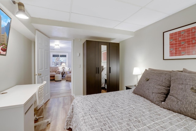 bedroom featuring a paneled ceiling and light wood finished floors