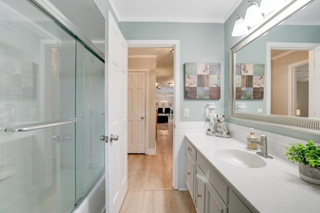 ensuite bathroom with ornamental molding, wood finished floors, combined bath / shower with glass door, connected bathroom, and vanity