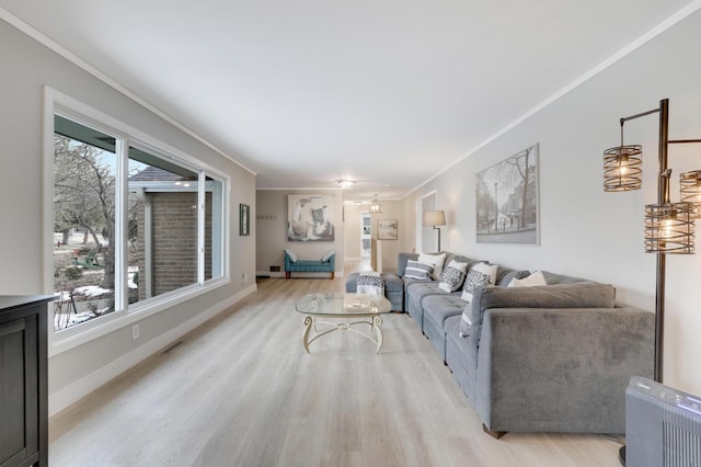 living room with a wealth of natural light, visible vents, light wood-style floors, and ornamental molding