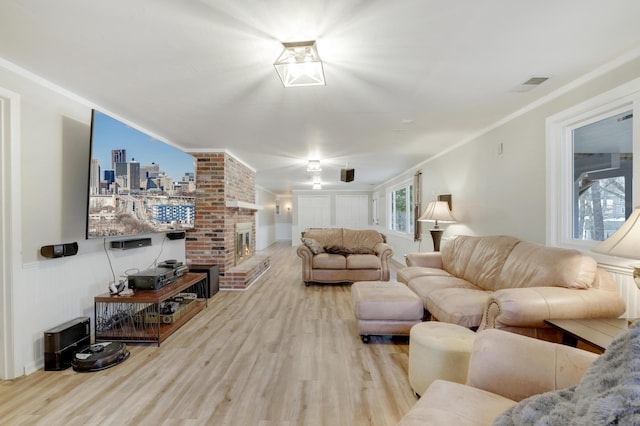 living room with visible vents, ornamental molding, a brick fireplace, and wood finished floors