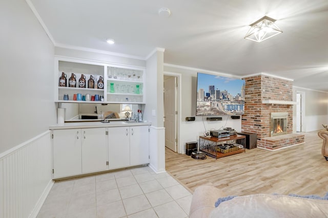 kitchen with a fireplace, white cabinetry, and ornamental molding