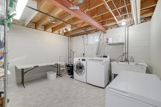 clothes washing area featuring a sink, laundry area, and washer and clothes dryer