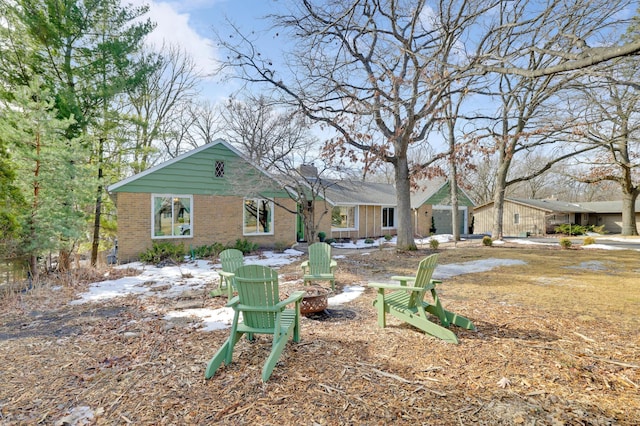 rear view of house featuring brick siding and an outdoor fire pit