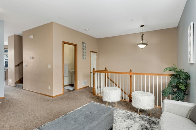 living area featuring carpet, visible vents, baseboards, and an upstairs landing