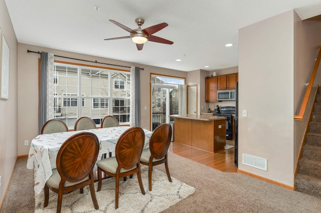 dining room featuring baseboards, stairs, visible vents, and light colored carpet