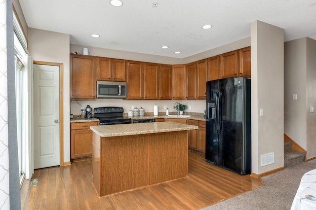 kitchen featuring brown cabinetry, light countertops, visible vents, and black appliances